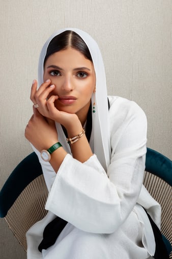 A woman matching a luxury watch with rose gold diamond earrings set with malachite