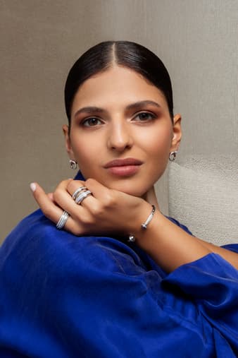 A woman wearing Possession luxury earrings and white gold diamond rings